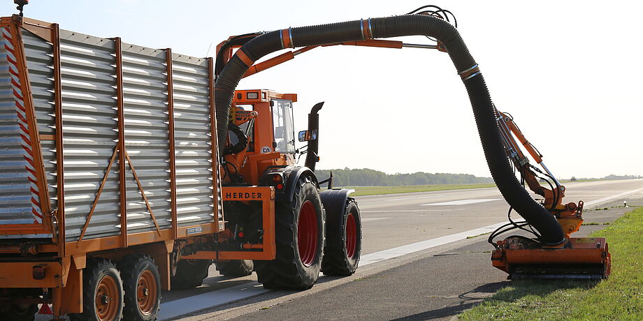 Ein Trecker mäht an der Landebahn Grasflächen