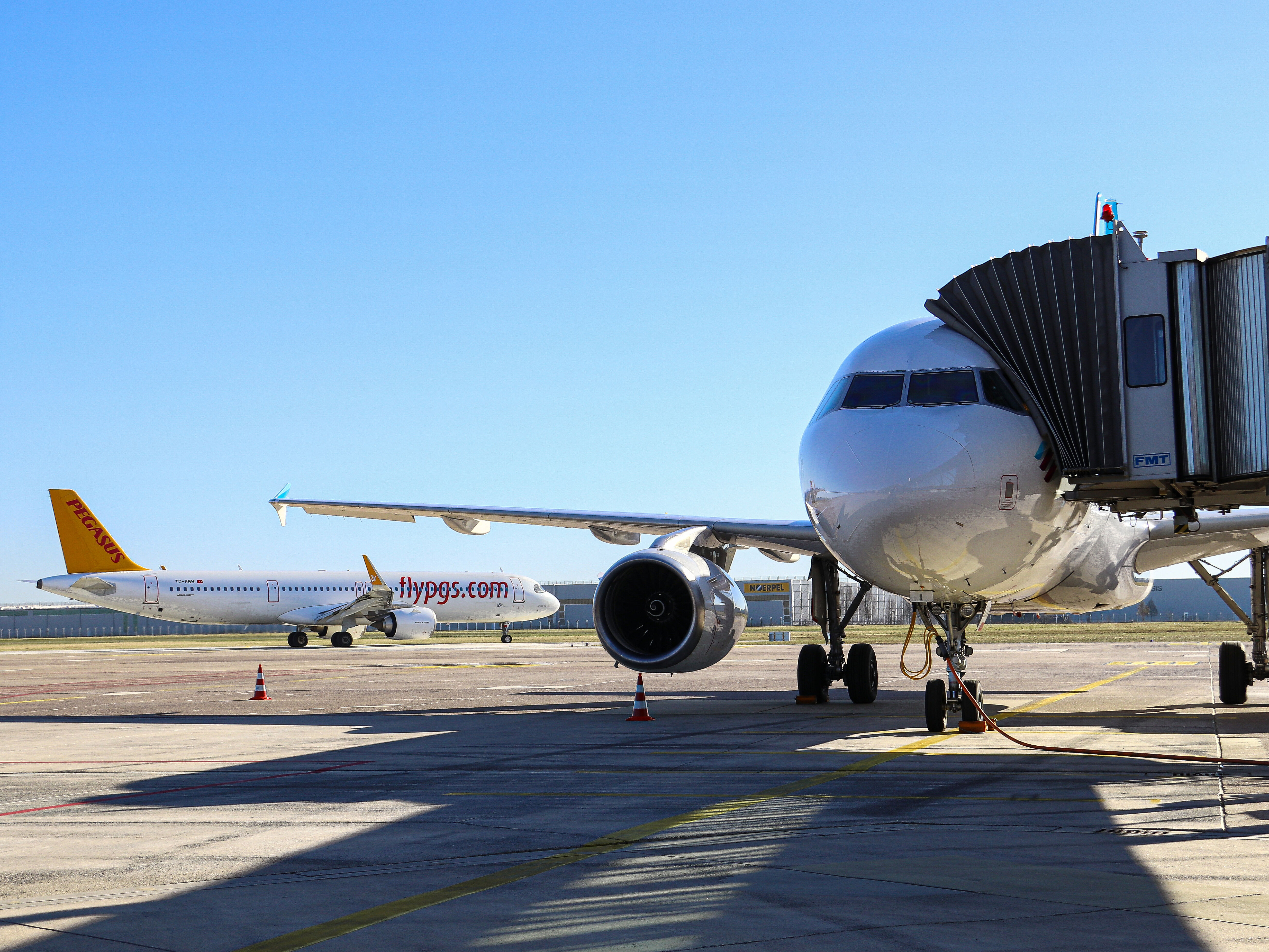 Im Vordergrund Eurowings Flugzeug mit angedockter Fluggastbrücke, im Hintergrund Maschine von Pegasus Airlines auf dem Vorfeld