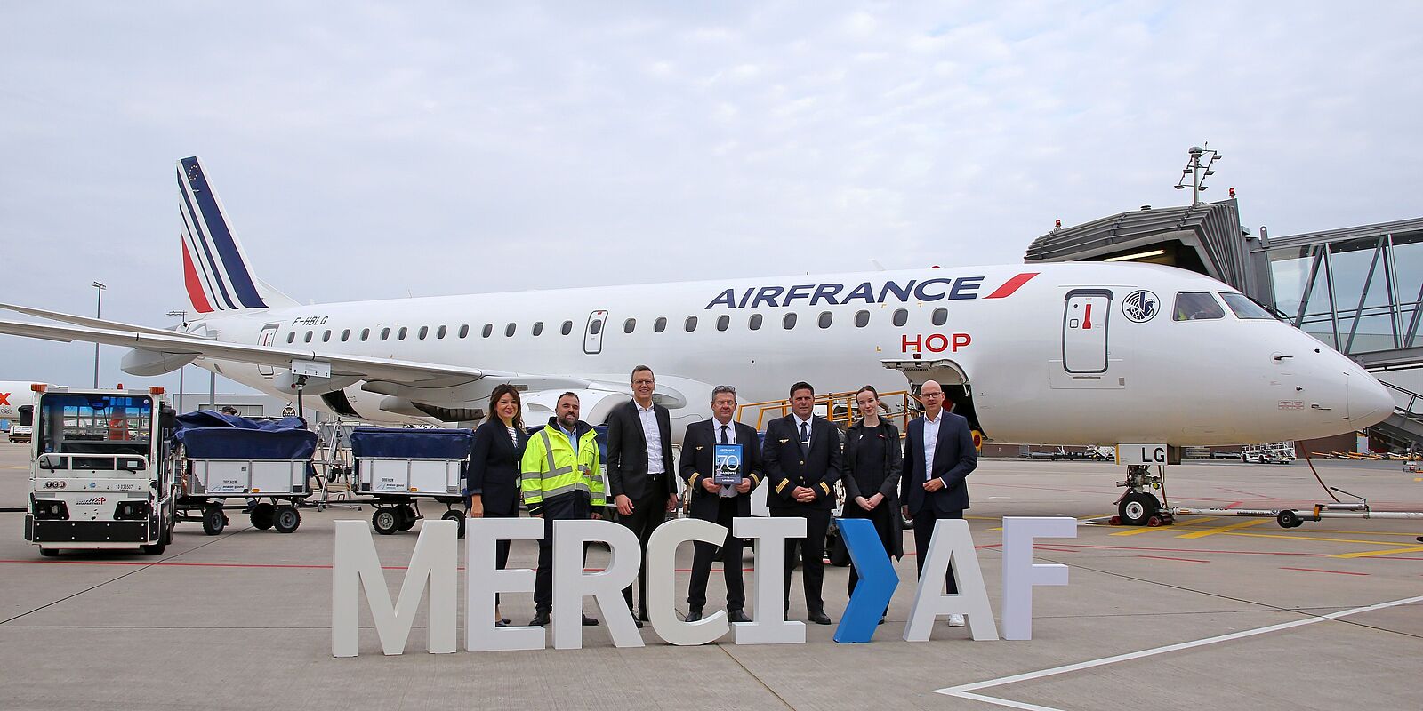 Flughafen-Chef steht mit der Crew und großen Buchstaben ("Merci AF") vor dem Flugzeug der Air France.