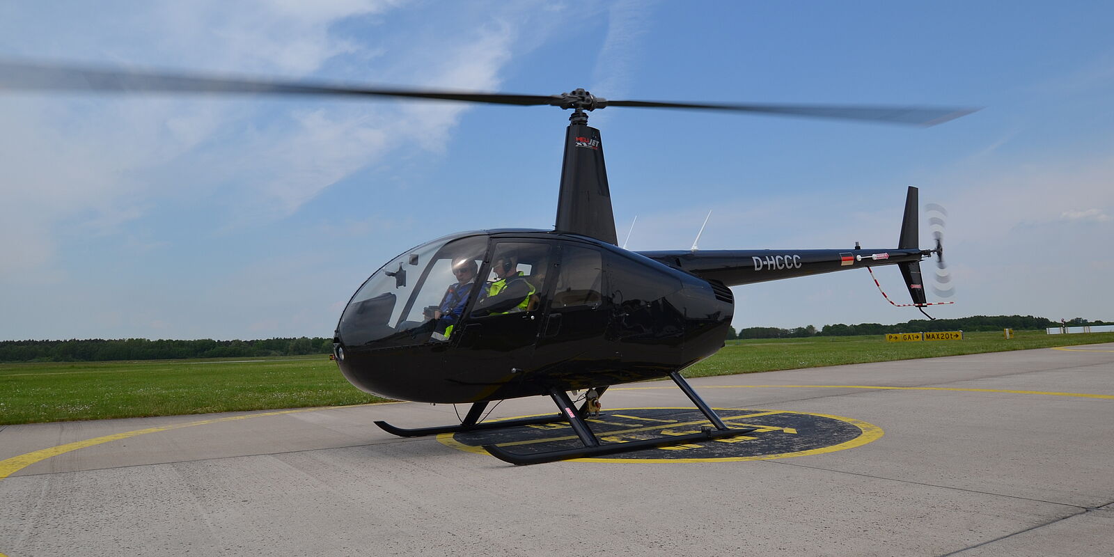 Bild einer schwarzen R44 (Helikopter) auf dem Vorfeld