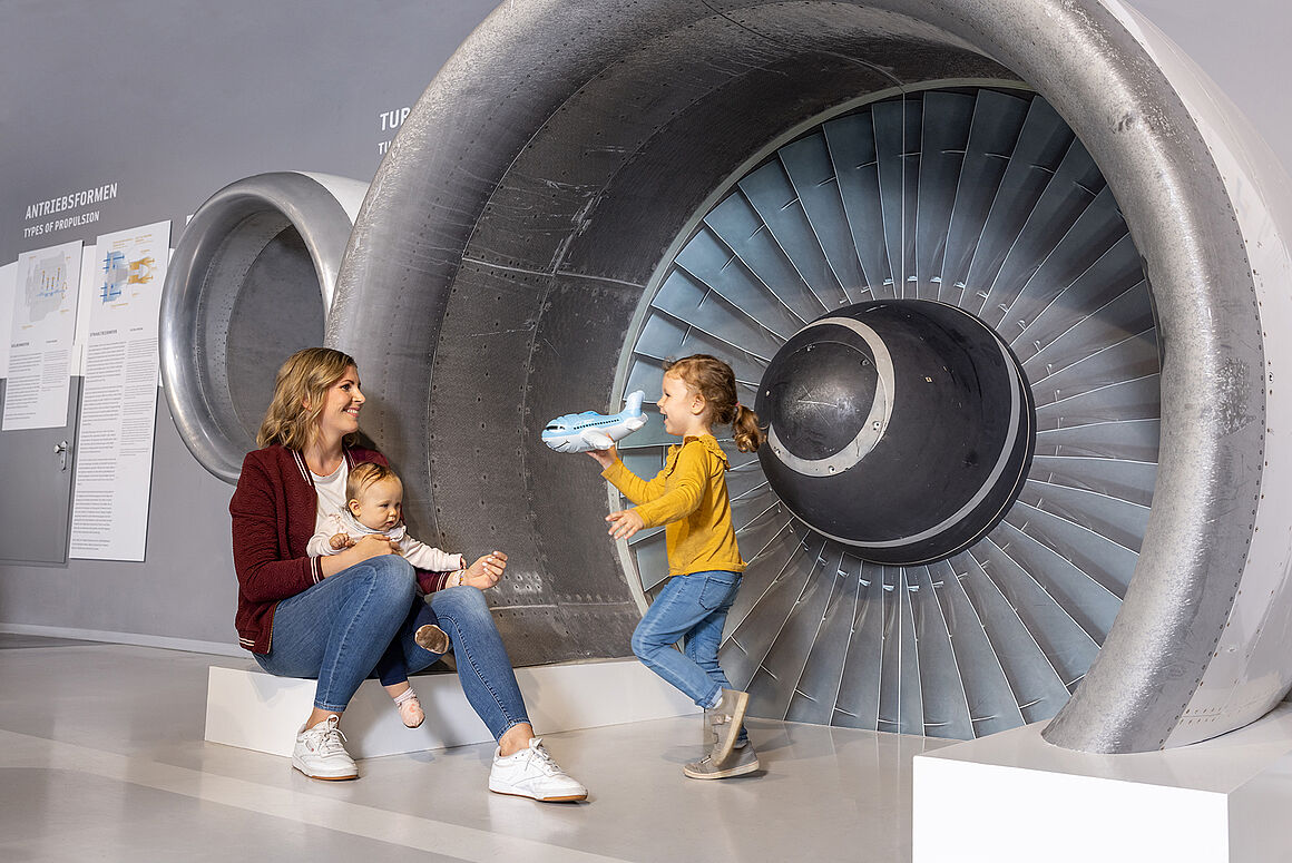 Bild Mutter und Kind vor einem Triebwerk