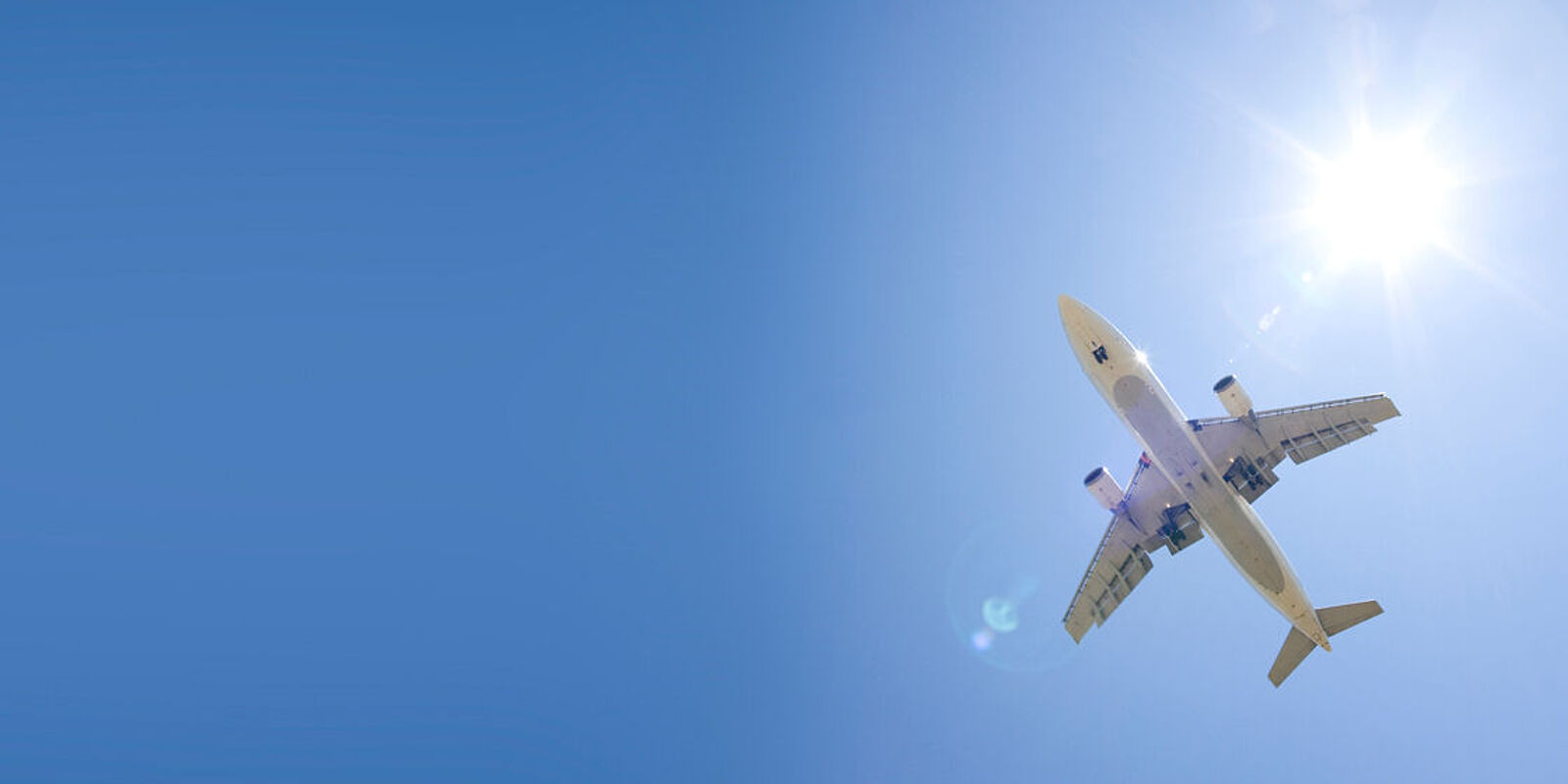 Fliegendes Flugzeug von unten fotografiert vor der Sonne